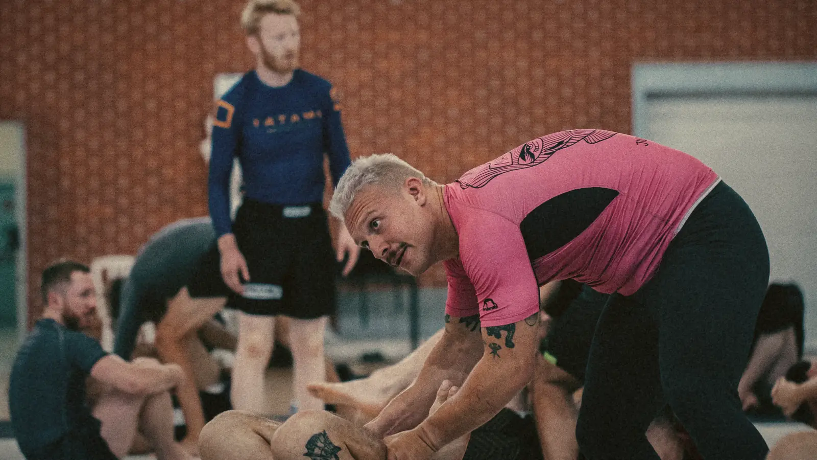 Der Coach zeigt eine Technik, die Gruppe übt auf der Matte.